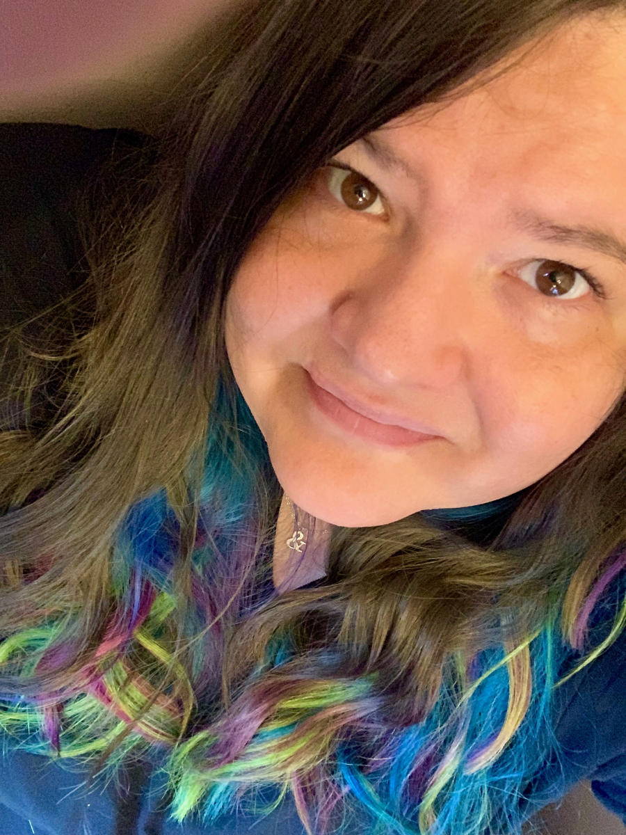A selfie of a woman in her mid-30s with brown, yellow, green, pink, and blue hair.